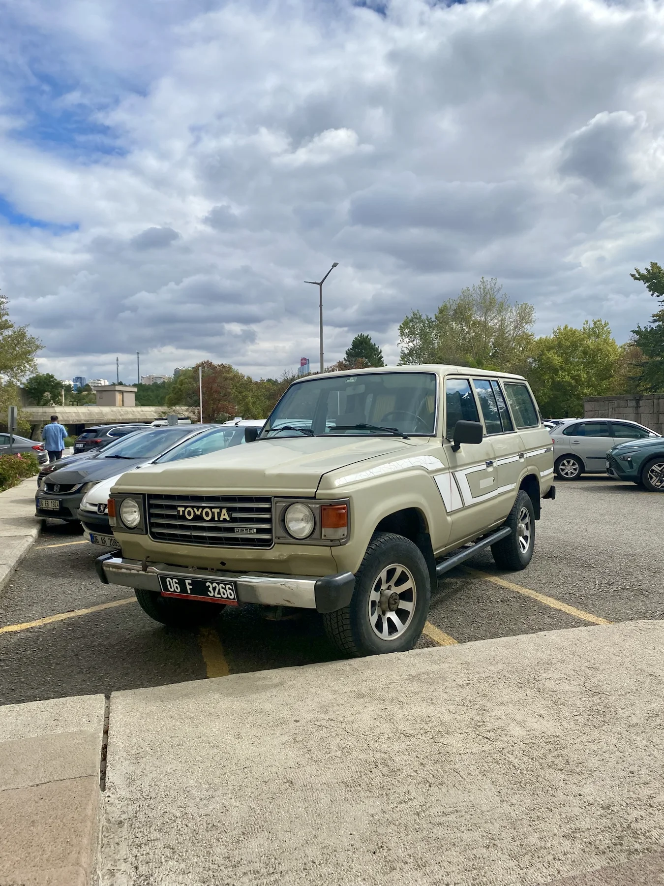Beige vintage Toyota Land Cruiser under a cloudy sky